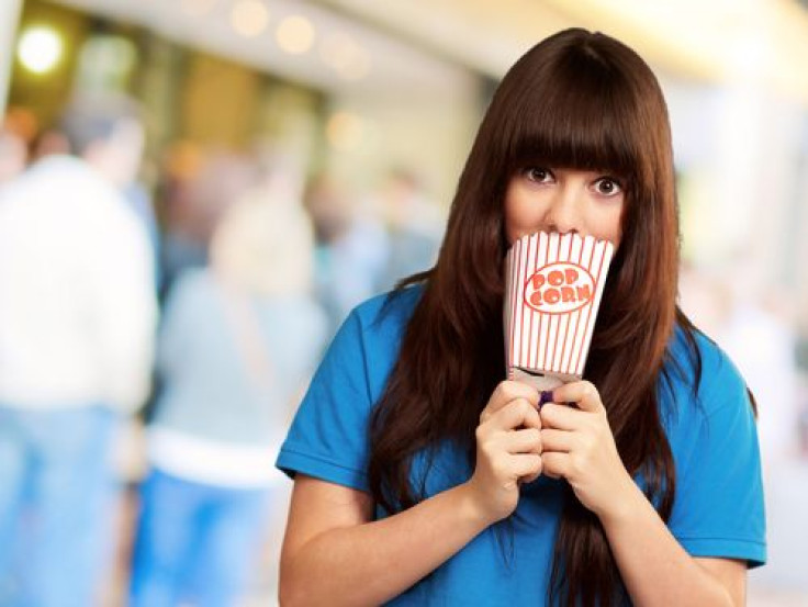 Girl covering mouth with empty popcorn packet outside