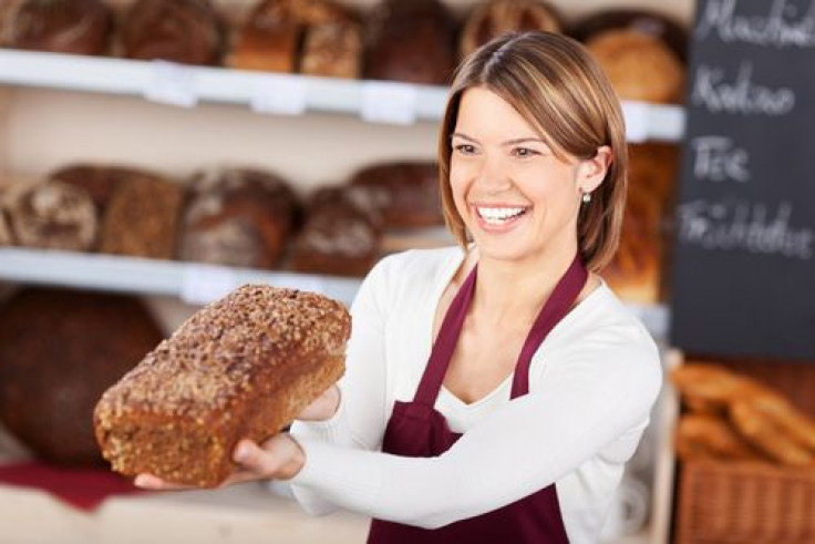 Bakery worker holding out a loaf of wholewheat 