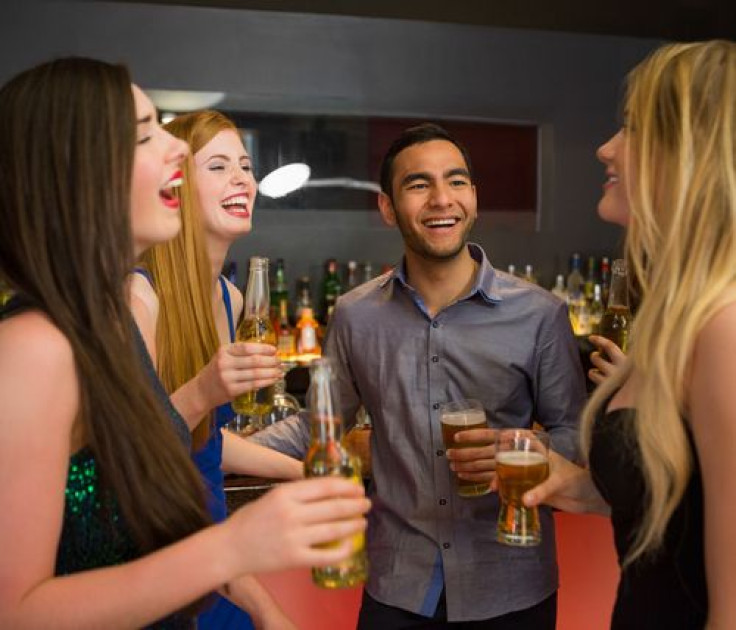 Friends laughing and chatting while having beer at the bar