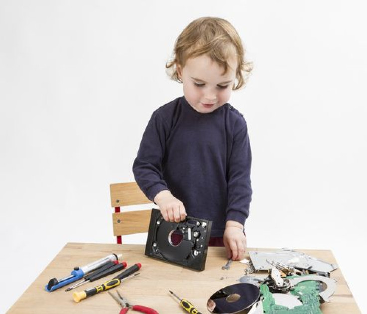 Preschooler with computer parts on wooden desk