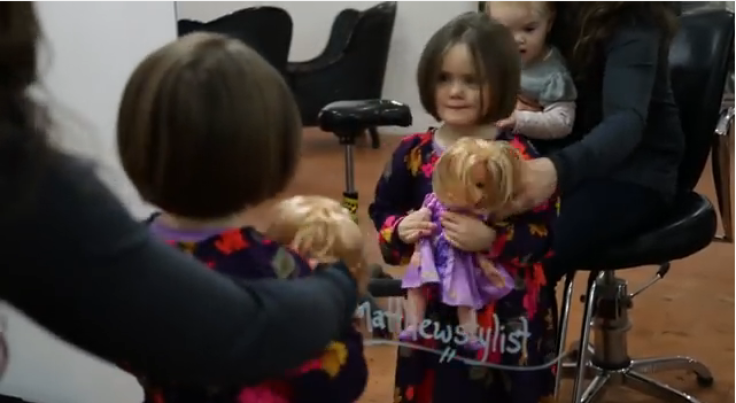 Emily James and Dolly look in front of the mirror after their haircuts 