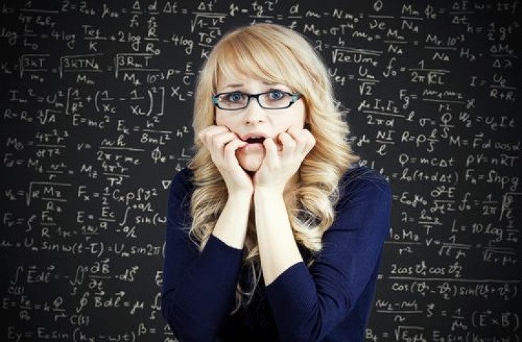 Woman feeling nervous and stressed in front of chalkboard with math problems