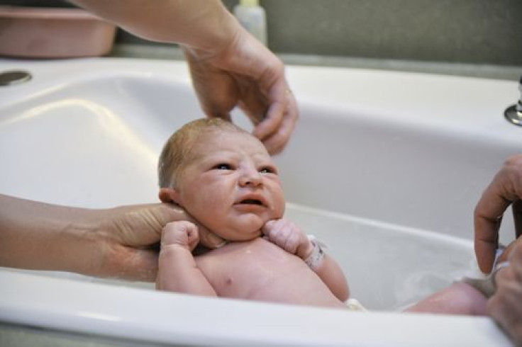 Newborn taking first bath in tub