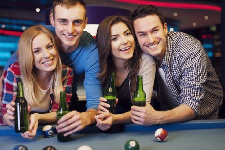 Friends drinking beers and playing pool