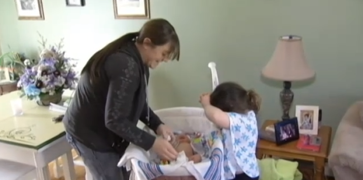 Scollin and daughter Kelsey help change Cole's diaper in crib