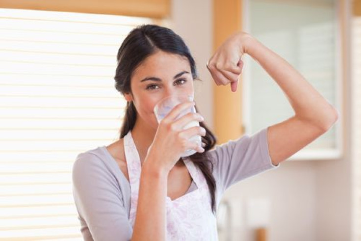 Woman drinking milk and flexing arm muscle 