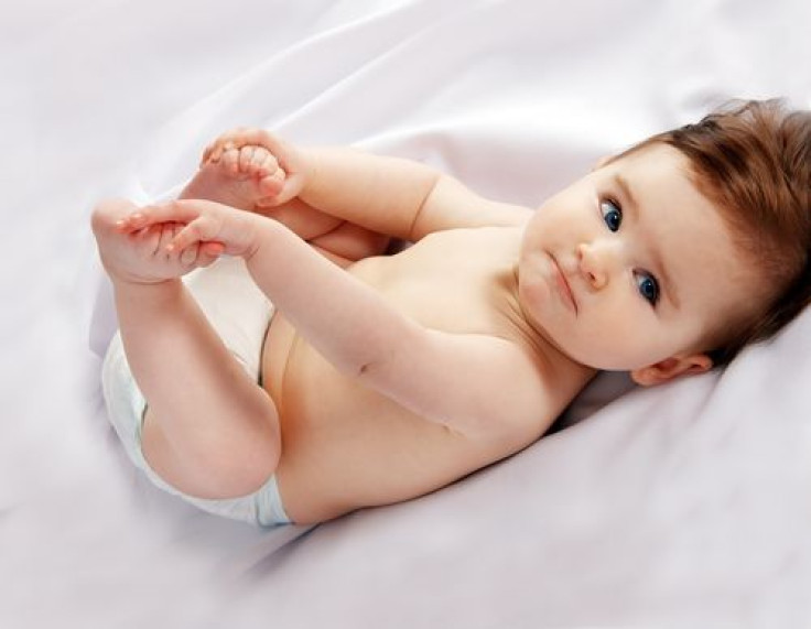 Baby holding feet with hands on blanket