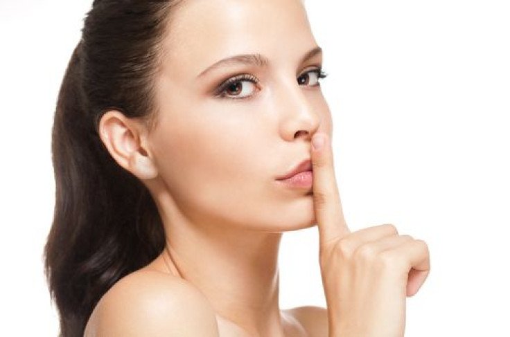 Woman holding index finger to lips