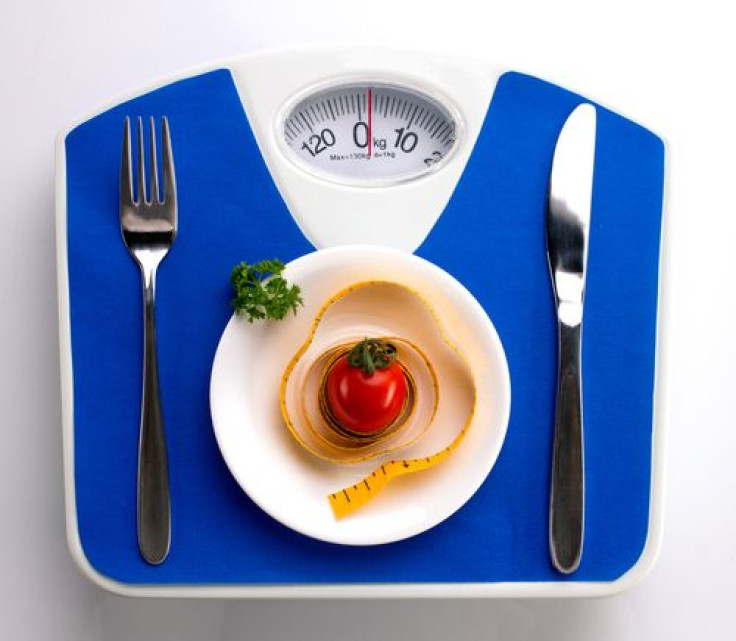 White plate with tomato and meal, fork and knife on blue scale