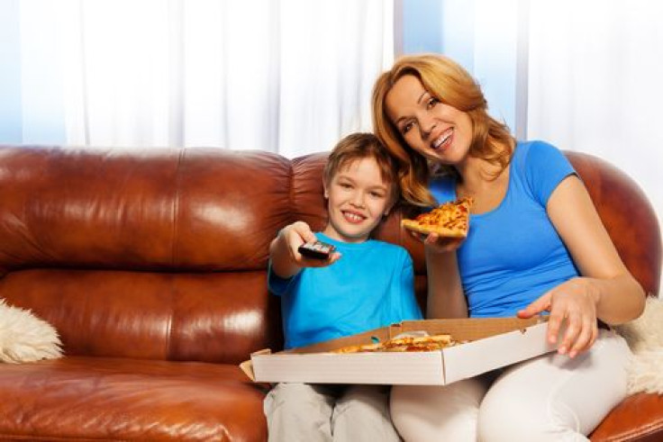 Kid and mother eating pizza while watching TV