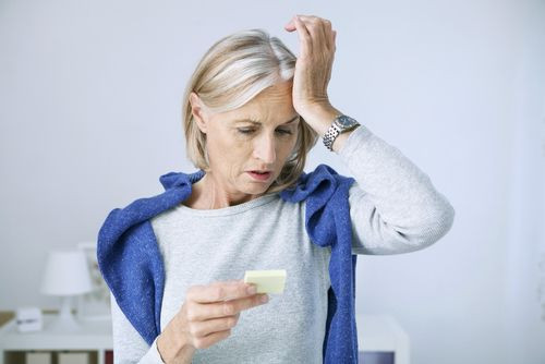 Woman reading note and holding hand to head