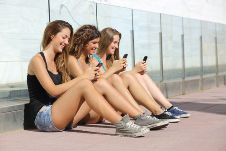 Girls on cellphones sitting outside