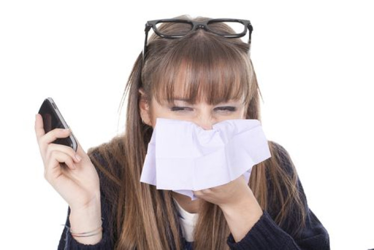 Woman holding cellphone and sneezing