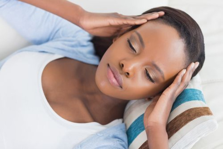 Woman lying on couch while having hands on head