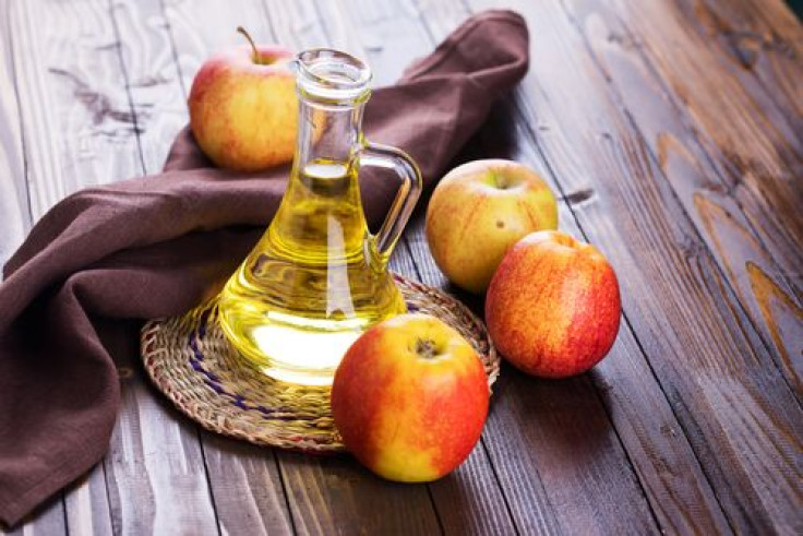 Apple vinegar and apples on wooden table