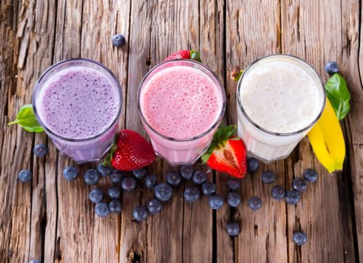 Fresh milk, strawberry, blueberry and banana drinks on wooden table, assorted protein cocktails with fresh fruits.