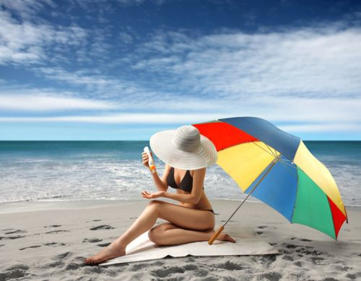 Woman in bikini applying sunscreen on the beach