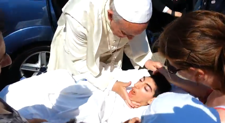 Pope Francis kisses bedridden girl lying on the road