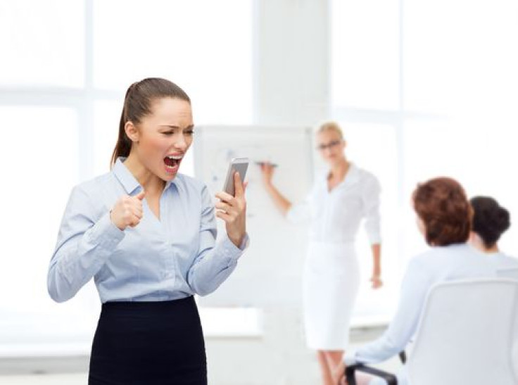 Woman screaming with smartphone in office