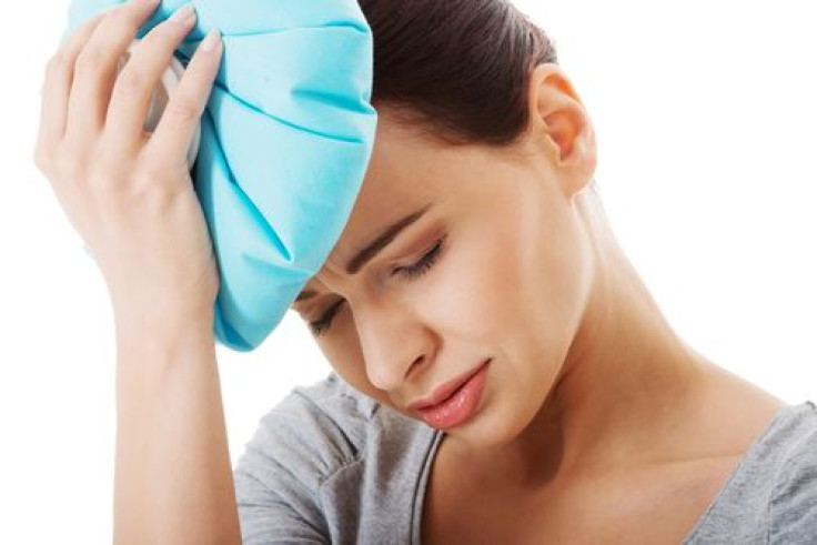 Woman having a headache and holding ice bag 