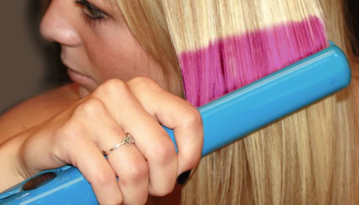 Woman uses flat iron to alter color and press a new hair pattern.
