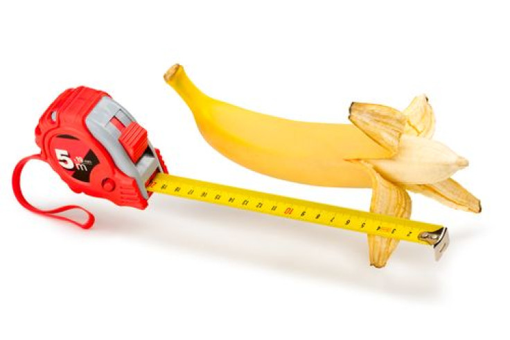 Man holding measuring tape next to penis