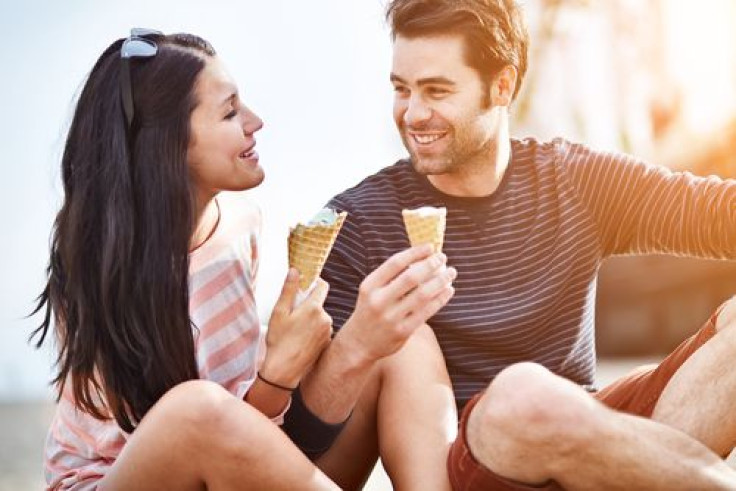 Couple at amusement park eating ice cream and laughing
