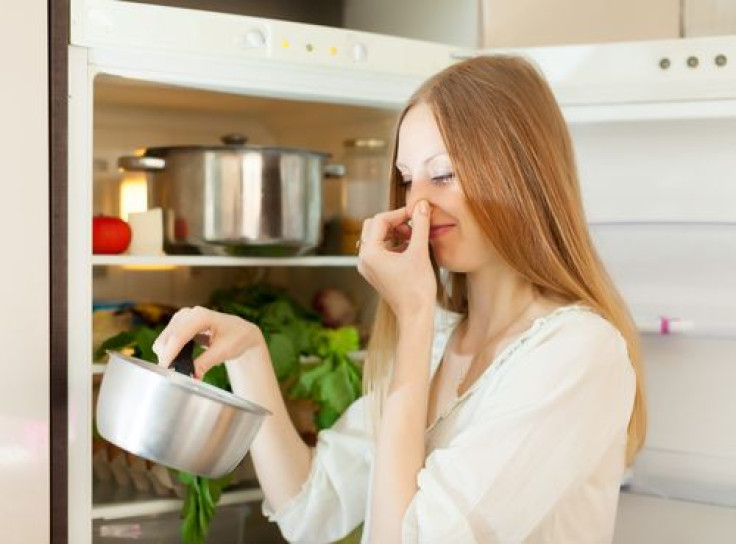 Woman hold nose and cooking pot because of bad smell