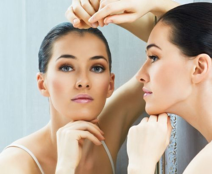 Woman looking in the mirror resting hand on head