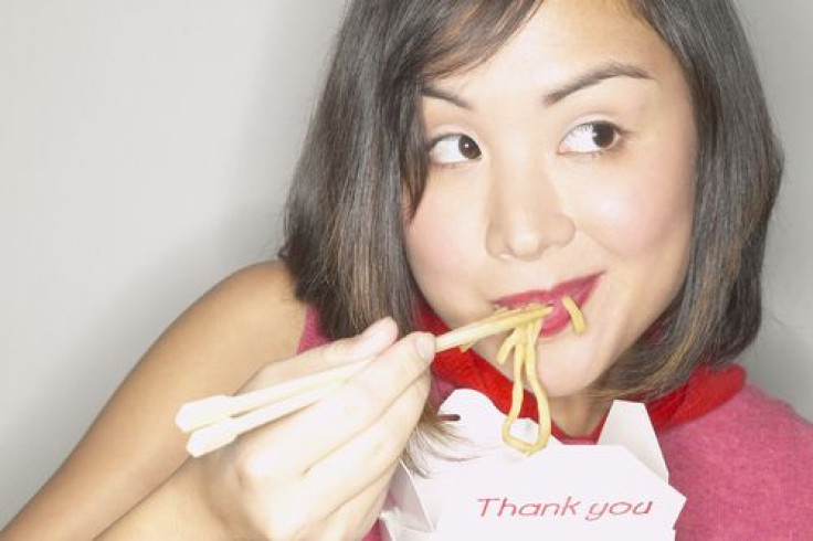 Woman eating Chinese takeout with chopsticks 