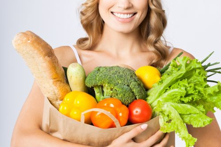 Woman smiling holding grocery bag with vegetables 