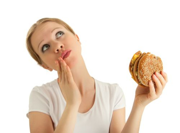 Woman holding burger in hand and looking up