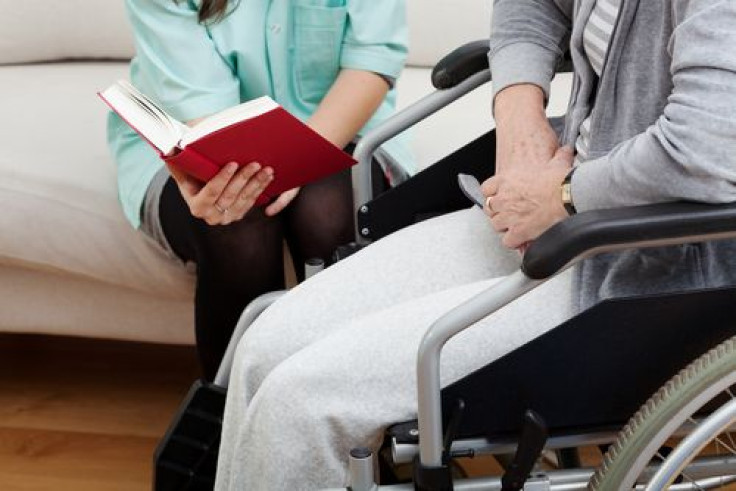 Caregiver reading to patient in wheelchair