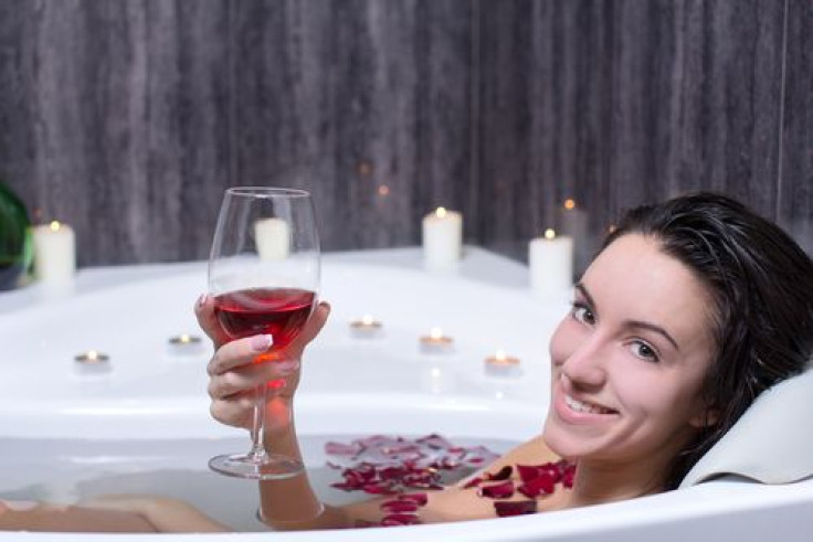Woman in bath with rose petals drinking wine