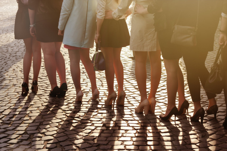 A row of women oin high heels standing on block paving