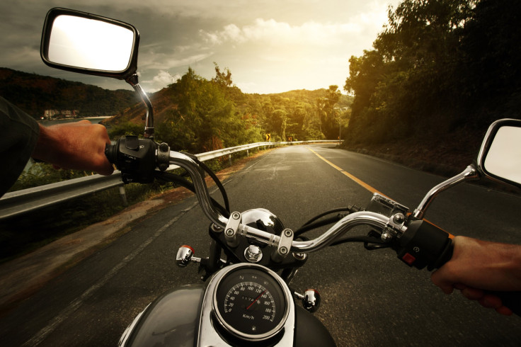 Driver riding motorcycle on an asphalt road through forest