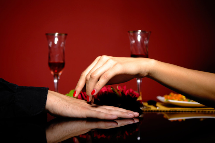 Close up of young couple at restaurant table with woman's hand resting on man's hand