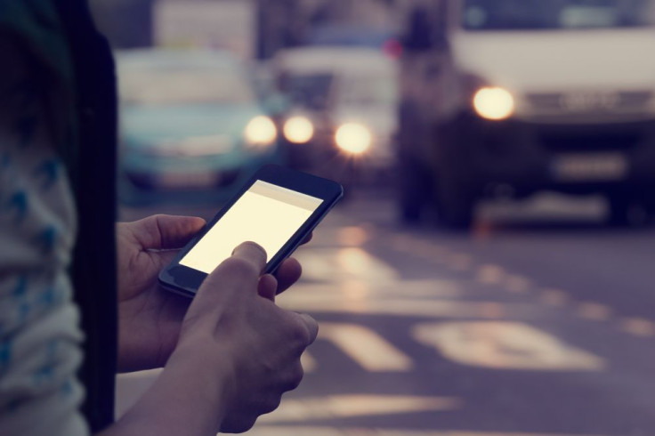 Man using cellphone outdoors with traffic in the background