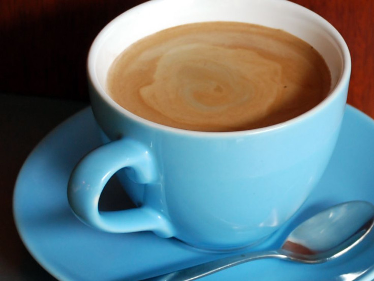 Coffee in a blue mug and blue plate with spoon on the side