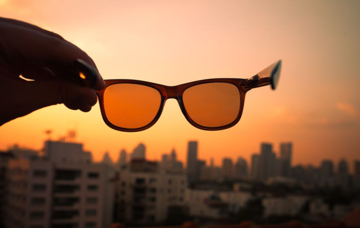 Orange glasses held up to sky