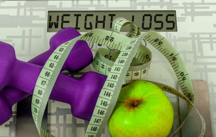 Dumbbells, apple, and measuring tape on scale