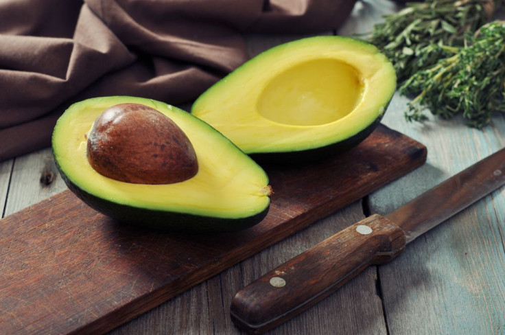 Fresh avocado on cutting board over wooden background