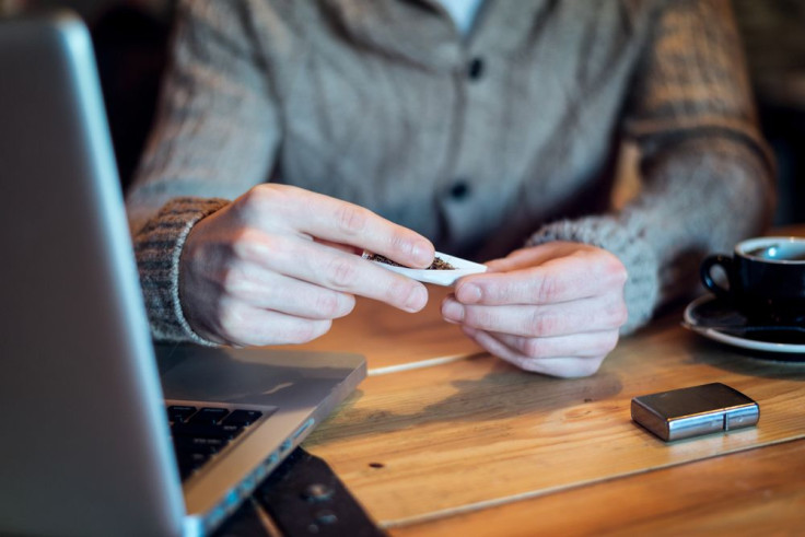 Man with marijuana and coffee on table next to computer