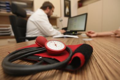 A doctor speaks to a patient as a sphygmomanometer, or blood pressure meter, lies on his desk on Sept. 5, 2012 in Berlin, Germany.