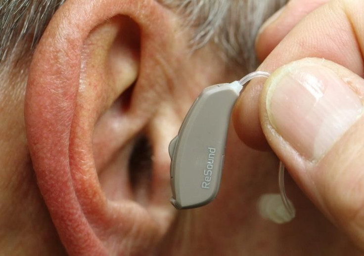 A man demonstrates a GN hearing aid. 