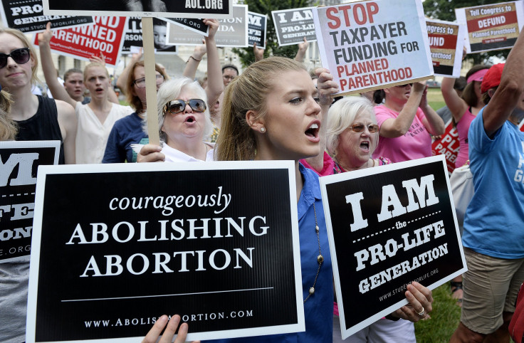 Protesters holding anti-abortion signs. 