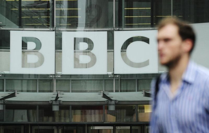 A man walks past BBC logo. 