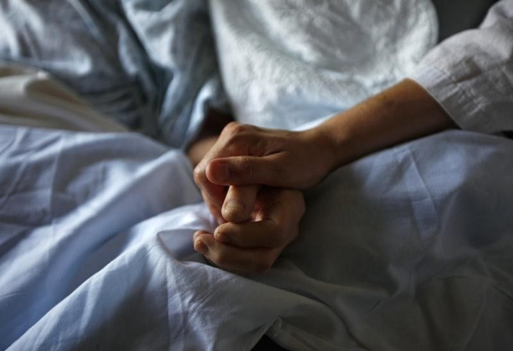 A woman holds hands with her ailing mother. 