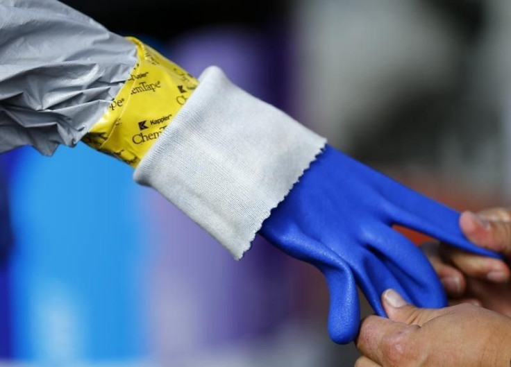 A health care worker removes a protective glove. 