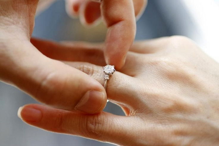 A man puts an engagement ring on a woman's finger. 